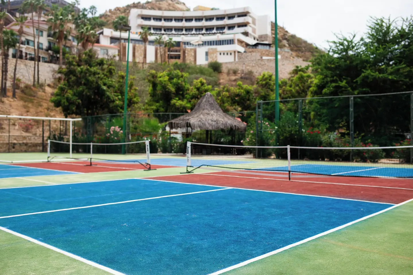 Colorful court surfaces and nets sit below hillside buildings at Sandos Finisterra.