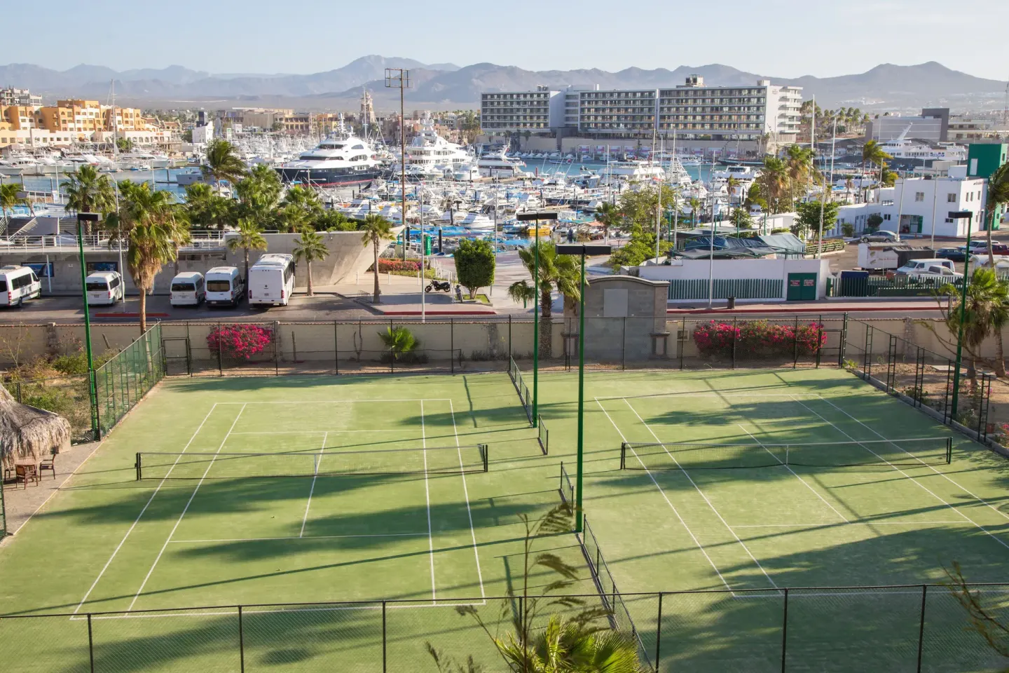 Tennis courts sit above the marina with boats beyond at Sandos Finisterra.