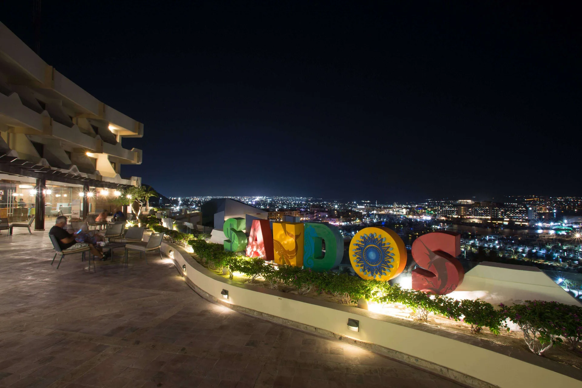 Night terrace with illuminated Sandos letters and city lights below at Sandos Finisterra.