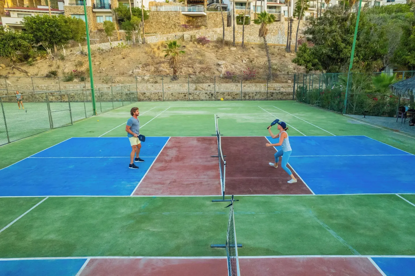 Two guests play pickleball on a fenced court at Sandos Finisterra.