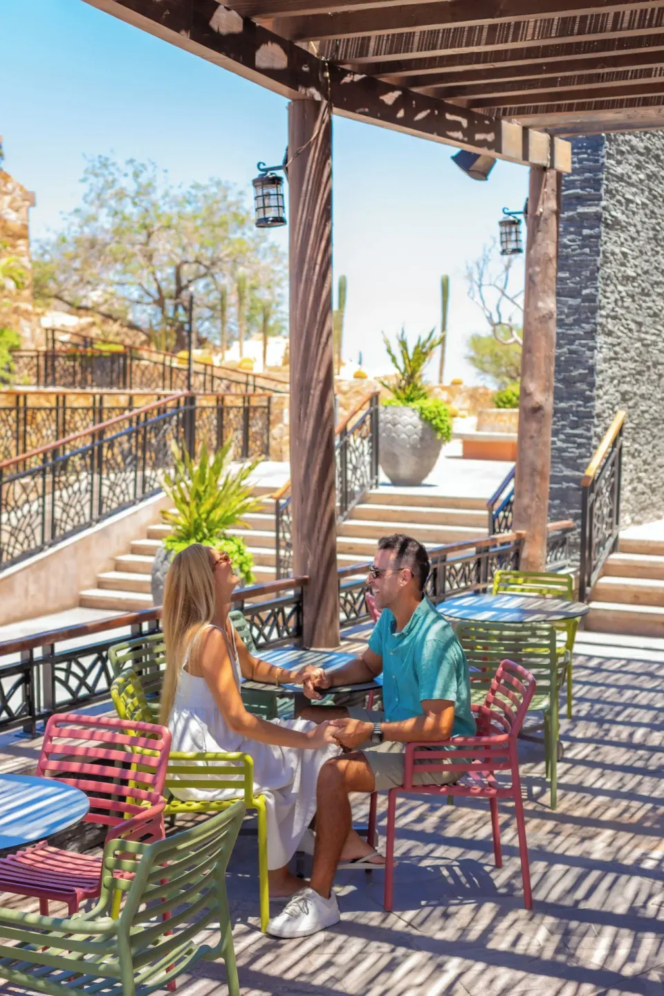 Couple seated at colorful patio tables in a shaded outdoor area at Sandos Finisterra.