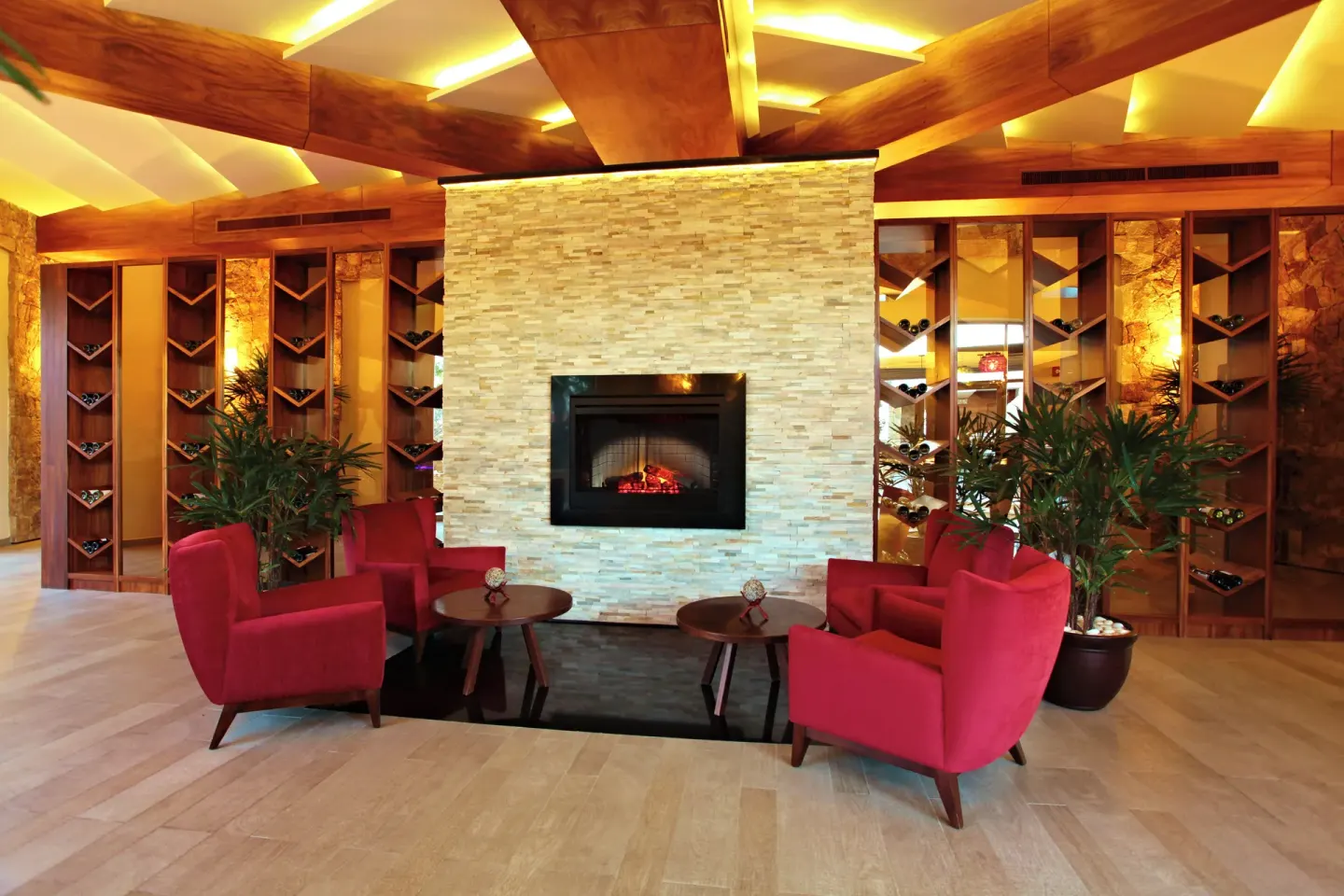 Lounge seating with red armchairs, fireplace, and wine racks at Sandos Finisterra.