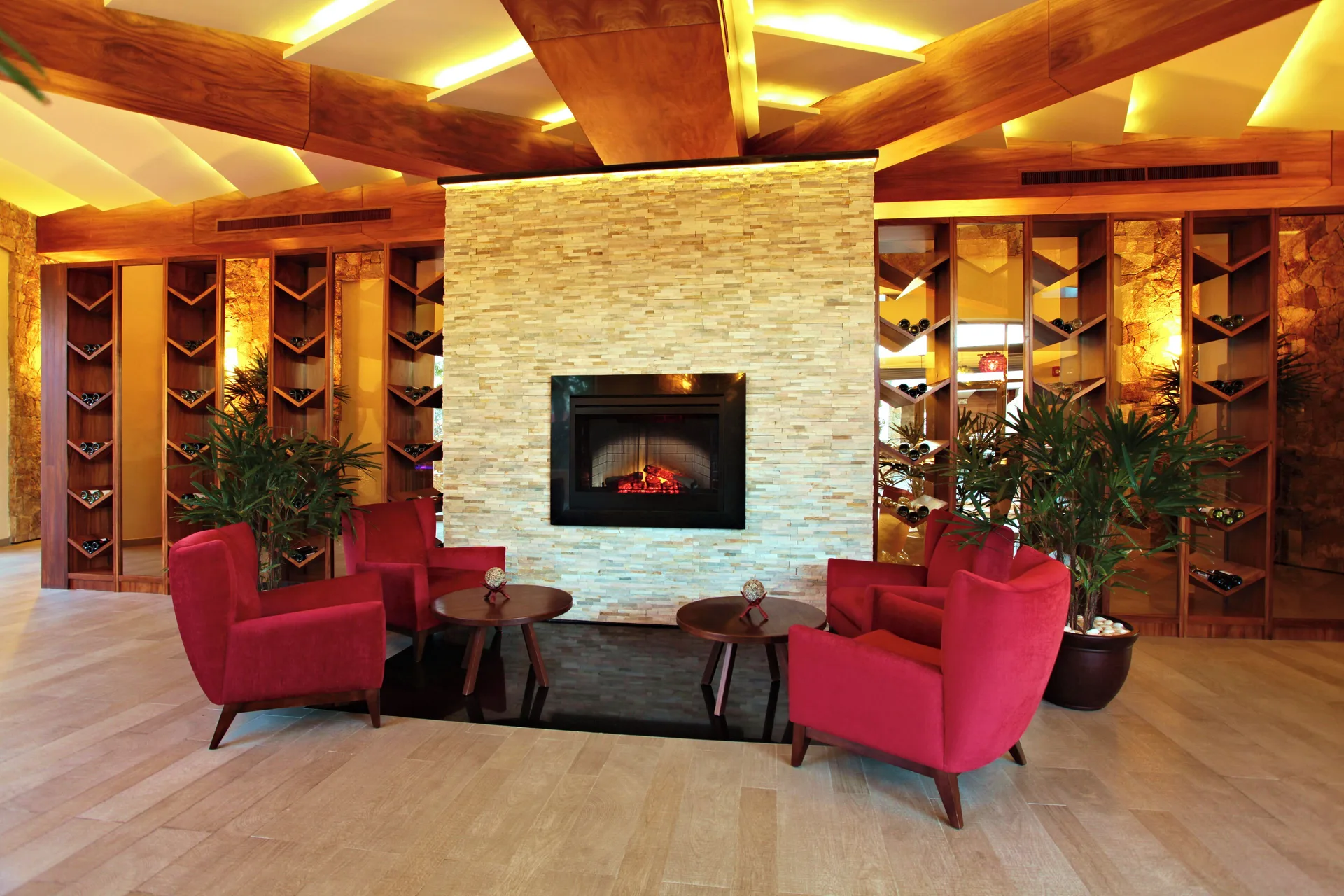 Lounge seating with red armchairs, fireplace, and wine racks at Sandos Finisterra.