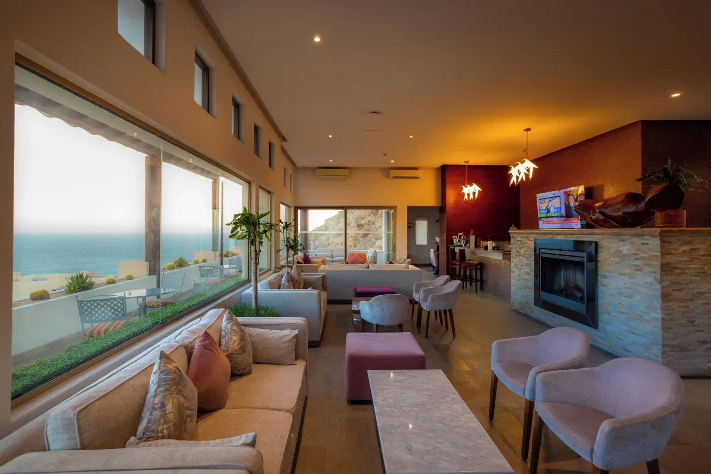 Ocean-view lounge with sofas, tables, and a bar at Sandos Finisterra.