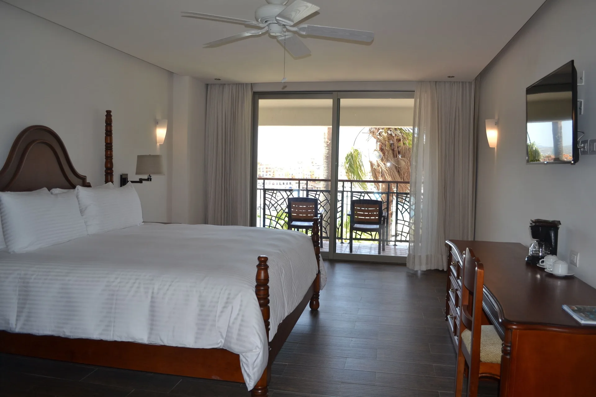 Casita Suite king bed, desk, wall TV, and balcony seating at Sandos Finisterra.