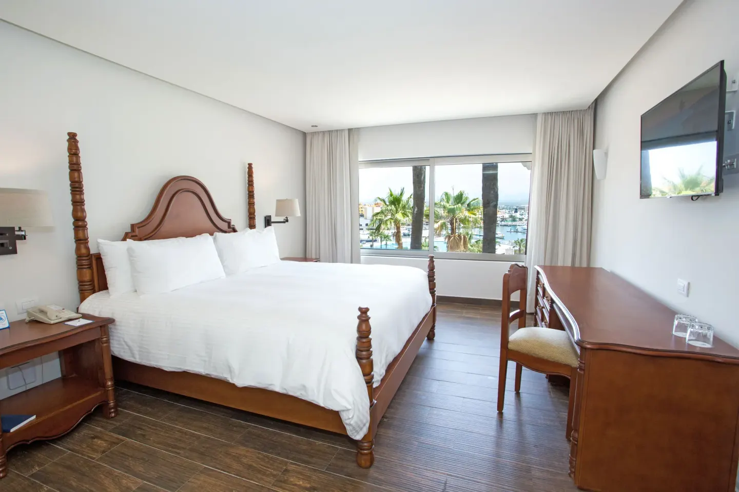 Casita Suite king bed with desk, wall TV, and large window at Sandos Finisterra.
