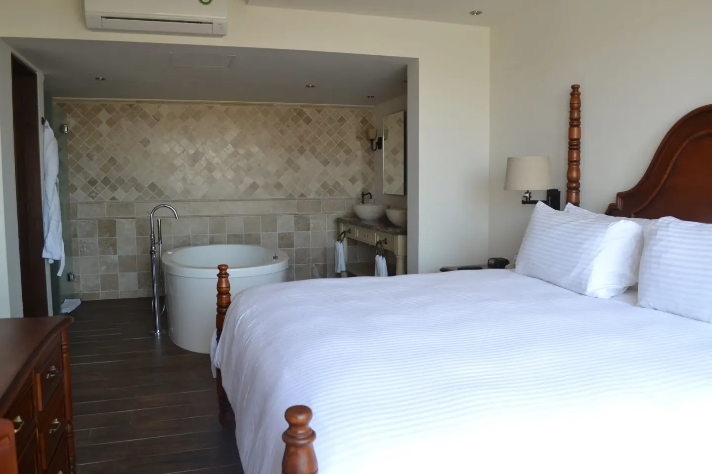 Casita Suite king bed with an open tiled bath and round soaking tub at Sandos Finisterra.