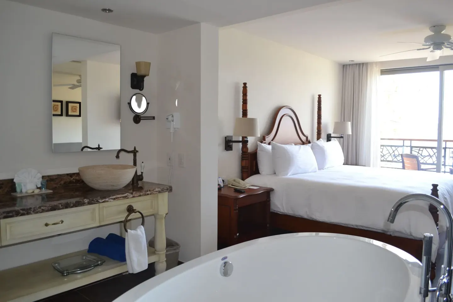 Casita Suite king bed beside an open vanity area and soaking tub at Sandos Finisterra.