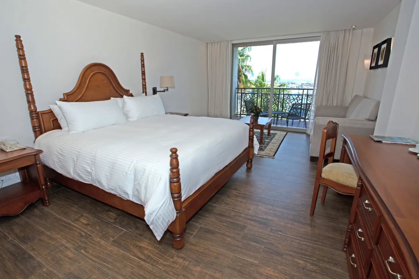Casita Suite king bed with sofa, desk, and balcony beyond at Sandos Finisterra.