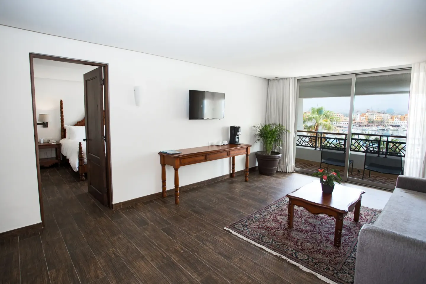 Casita Suite living room with sofa, coffee table, TV, and balcony at Sandos Finisterra.