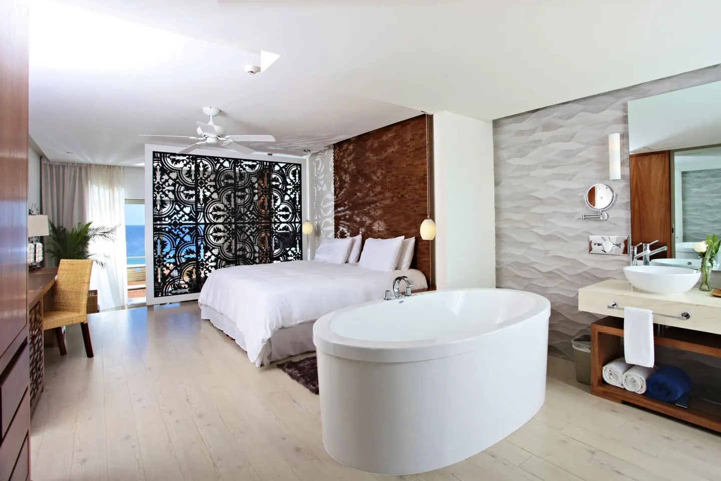 Finisterra Suite with king bed, oval tub, vanity, and decorative screen at Sandos Finisterra.