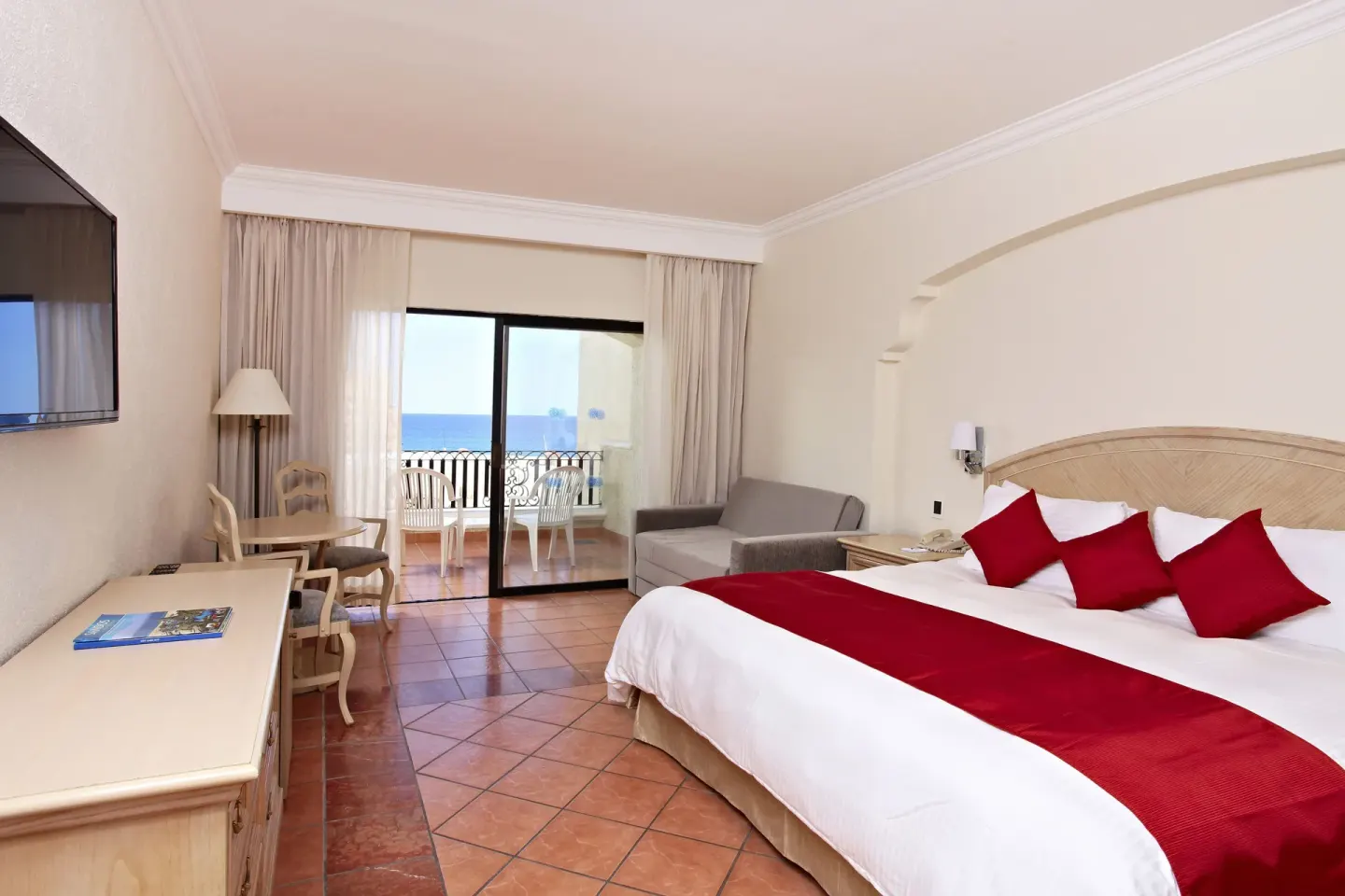 Finisterra Suite king bed with red accents and balcony view at Sandos Finisterra.