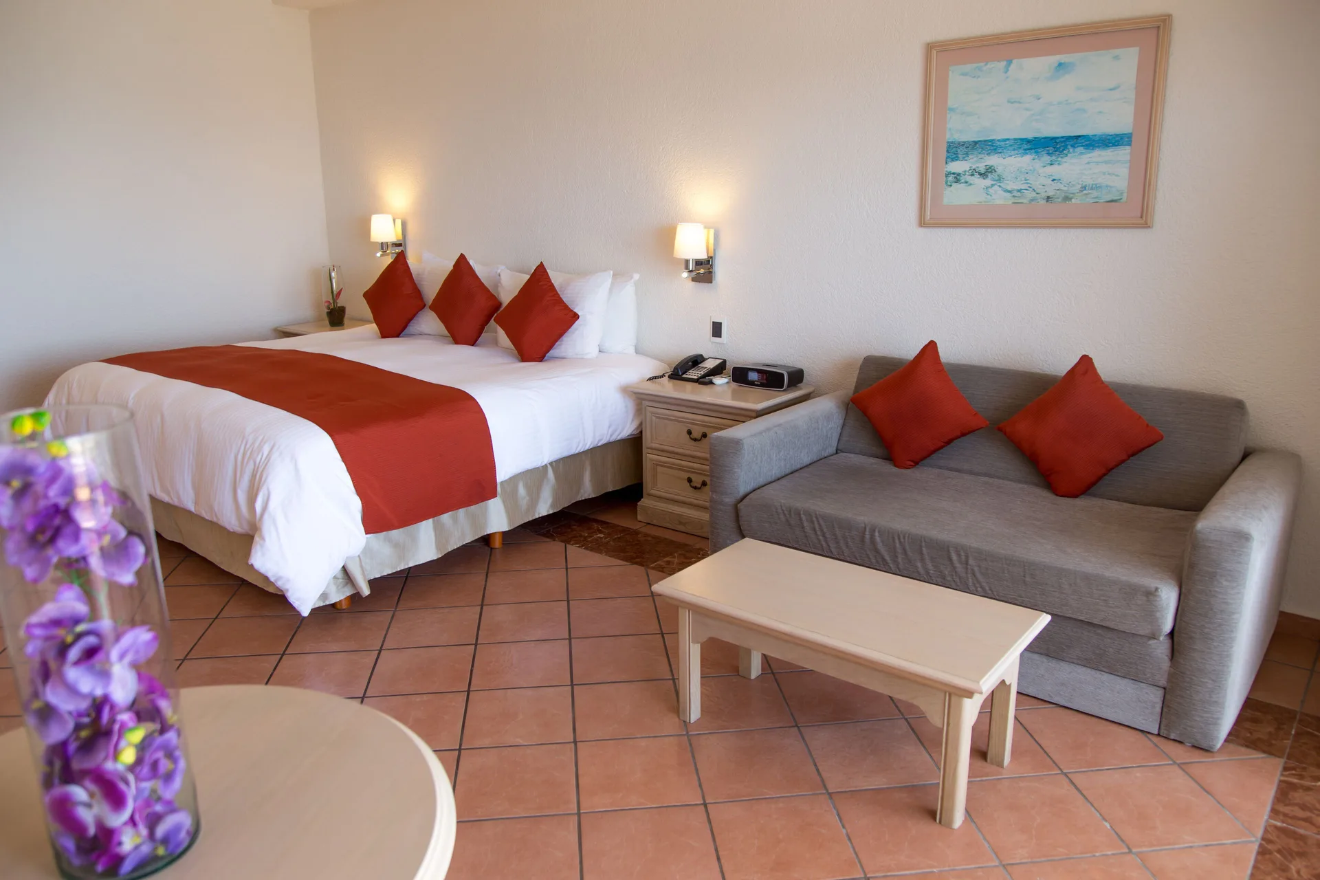Junior Room Ocean View at Sandos Finisterra with king bed, sofa, coffee table and red accents.