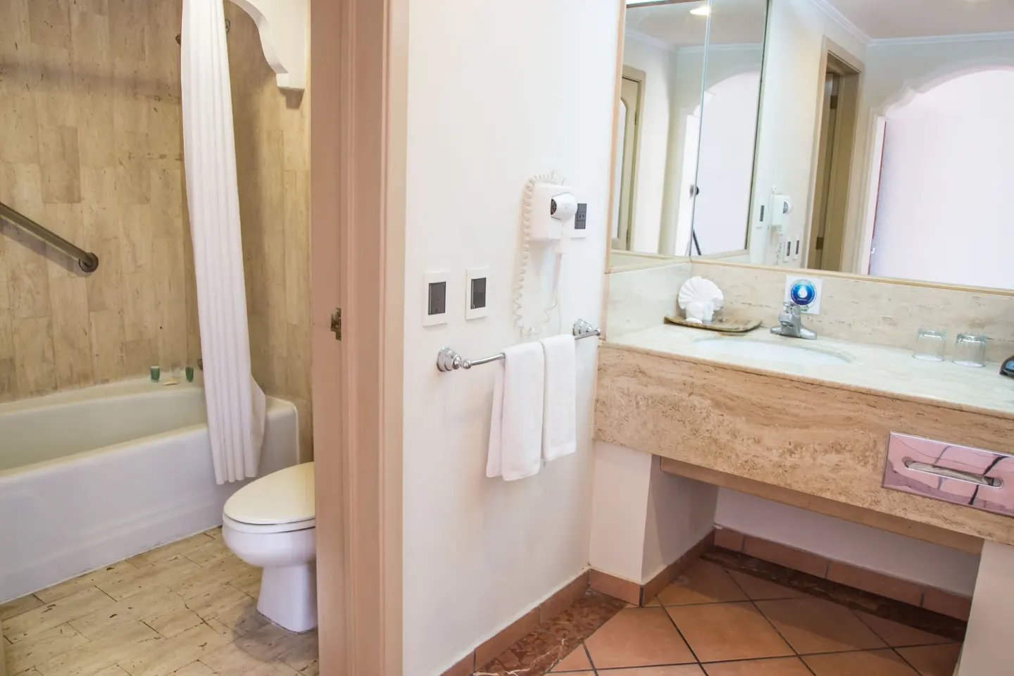 Junior Suite Garden View bathroom with tub-shower, toilet and vanity at Sandos Finisterra.