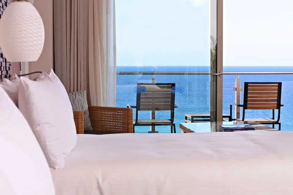 Junior Suite bed facing a balcony and ocean view at Sandos Finisterra.
