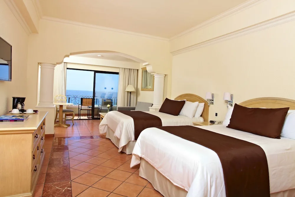 Junior Suite with two beds, tile floor, balcony, and ocean view at Sandos Finisterra.