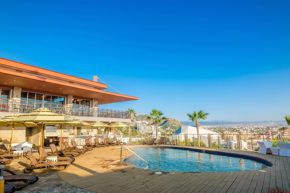 Pool deck with loungers, umbrellas, and city views at Sandos Finisterra.