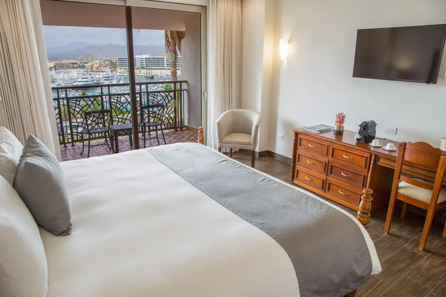 Marina Bay View king bed room with TV, desk, and balcony at Sandos Finisterra.