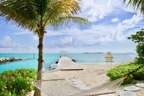 Beach hammock beside a white pier and turquoise water at Sandyport Beach Resort.