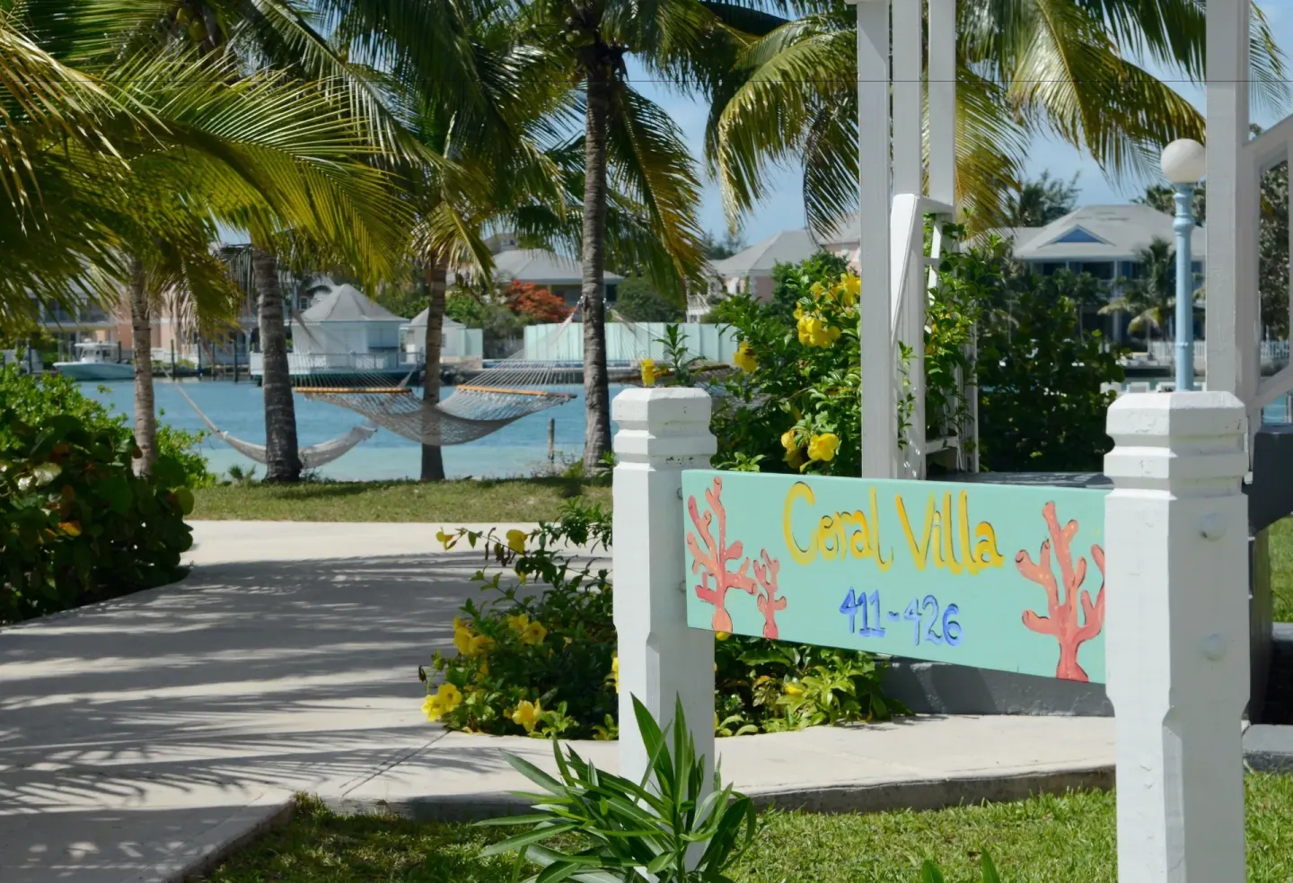 Coral Villa sign, palms, hammocks, and lagoon are visible at Sandyport Beach Resort.