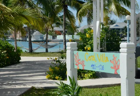 Coral Villa sign, palms, hammocks, and lagoon are visible at Sandyport Beach Resort.