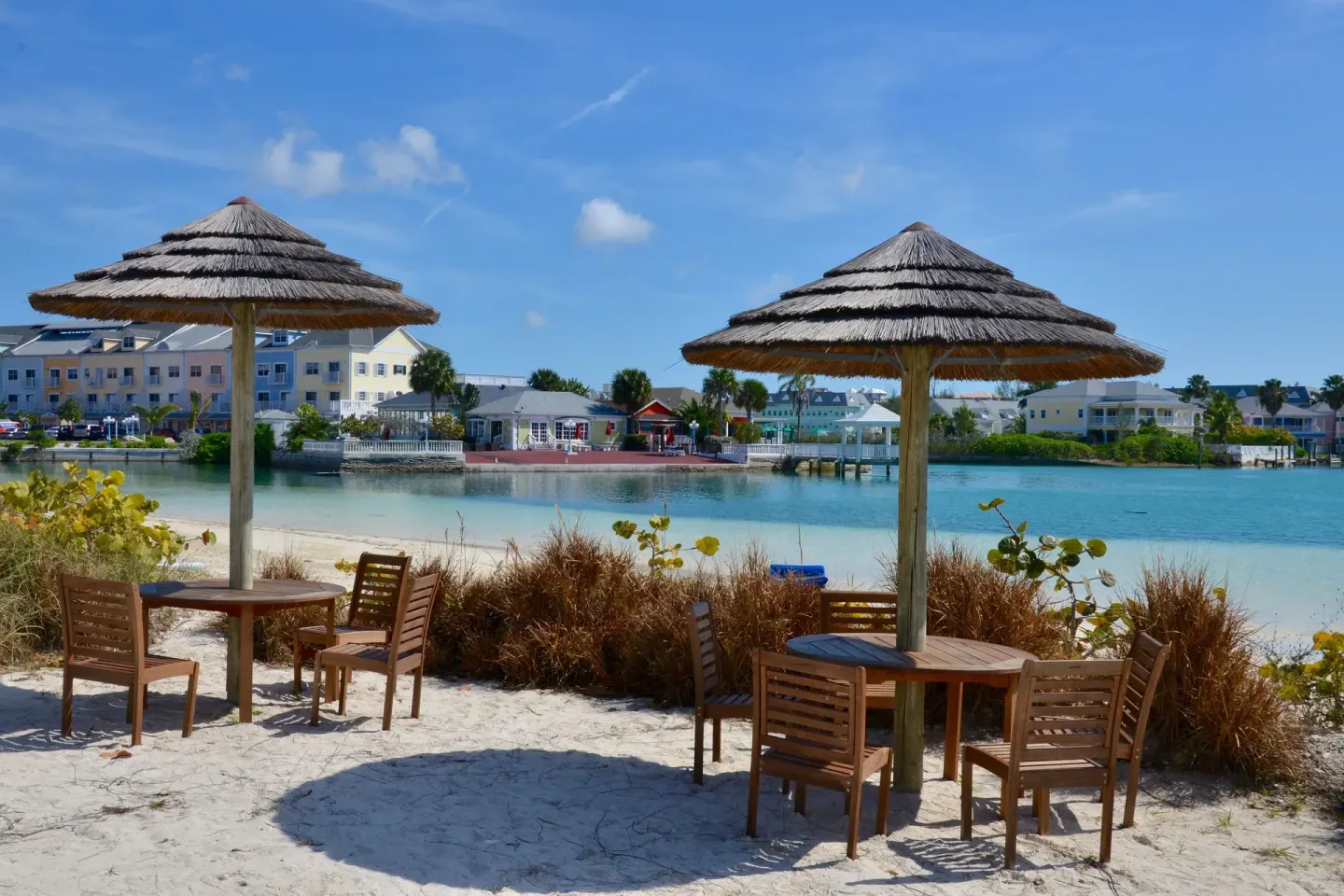Beach tables with thatched umbrellas beside the lagoon at Sandyport Beach Resort.