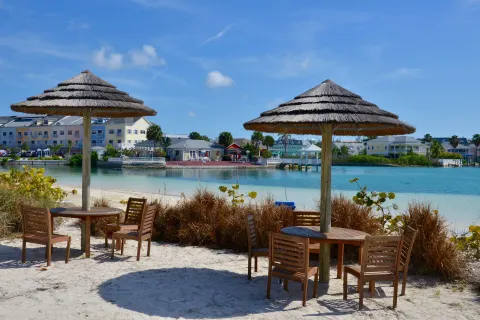 Beach tables with thatched umbrellas beside the lagoon at Sandyport Beach Resort.
