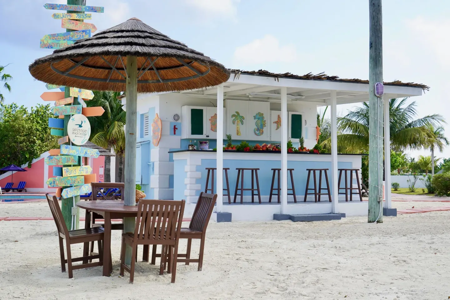 Sandy outdoor bar with stools and thatched seating at Sandyport Beach Resort.