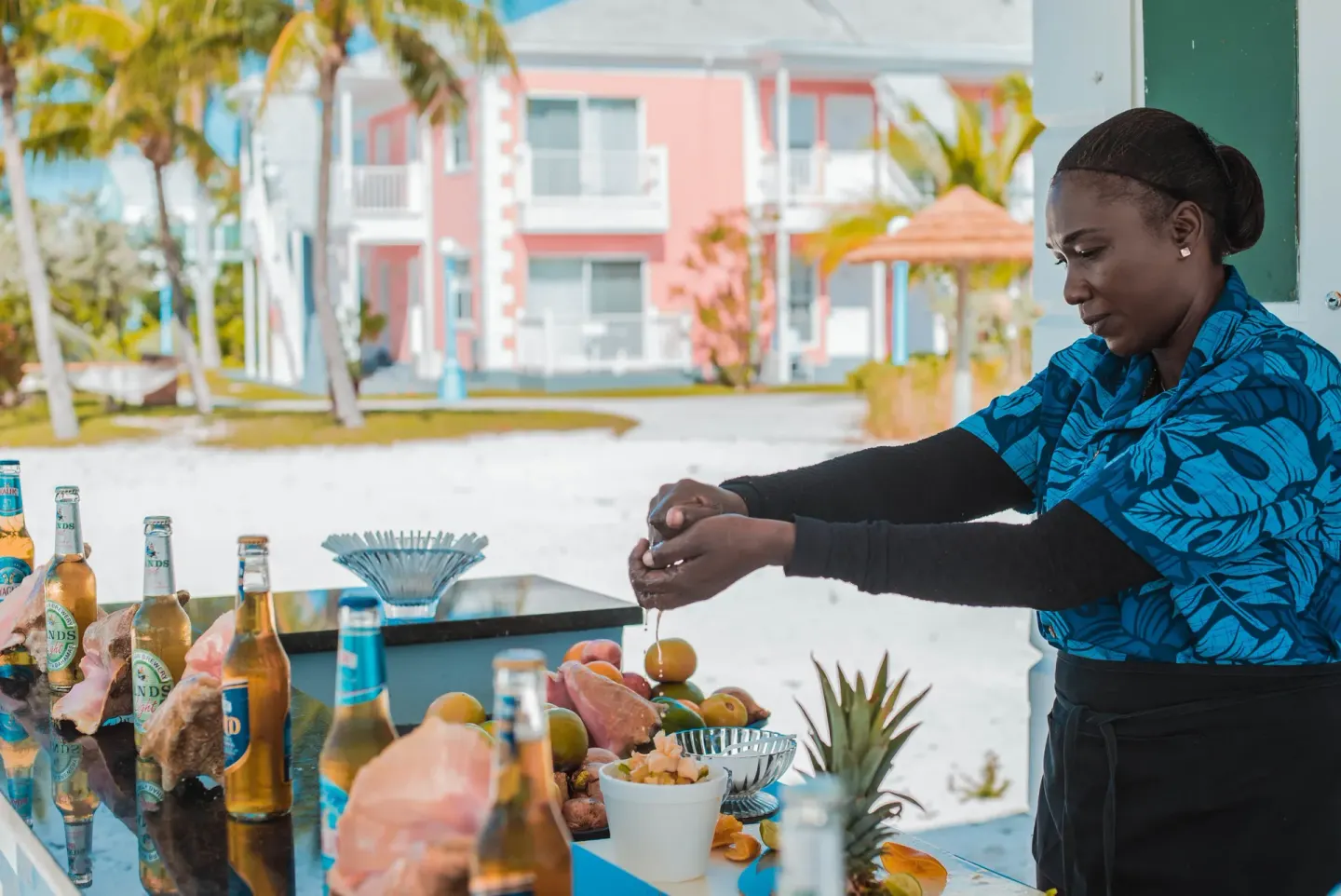 Staff member preparing fruit at an outdoor bar at Sandyport Beach Resort.