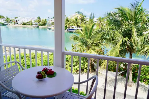 Deluxe suite balcony table with palm and canal views at Sandyport Beach Resort.