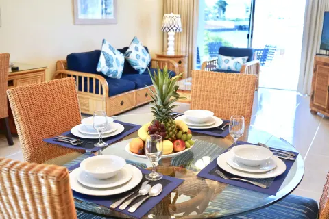Dining table, fruit bowl, and blue sofa seating in a suite at Sandyport Beach Resort.