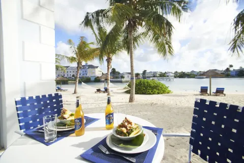 Patio table with meals and drinks facing the sandy lagoon at Sandyport Beach Resort.
