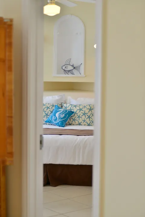 Bedroom doorway view of a white bed with coastal pillows at Sandyport Beach Resort.
