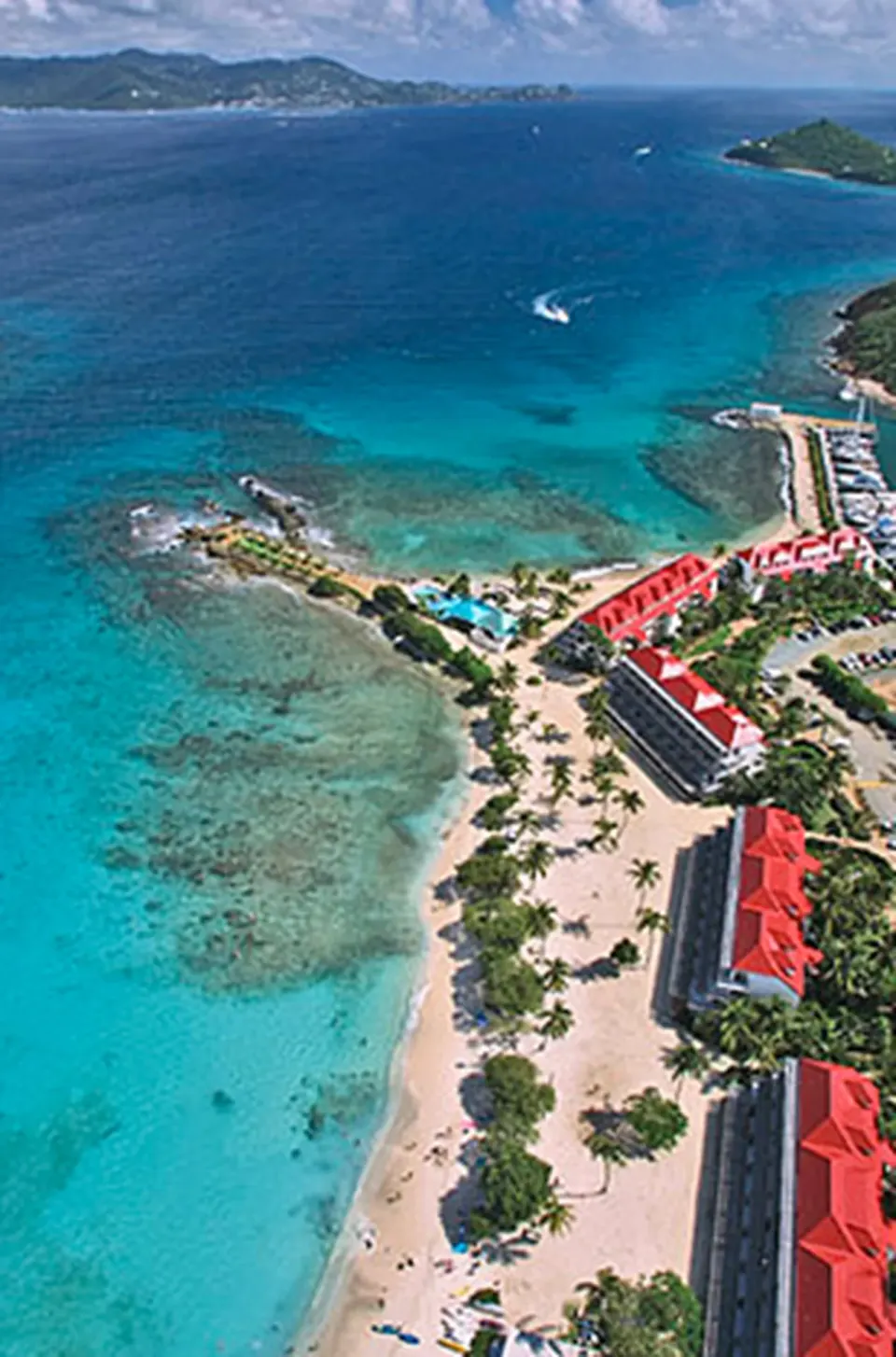 Aerial view of beach, reef, and red-roofed buildings at Sapphire Beach Resort.