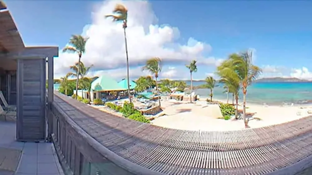 Beachfront balcony view over sand, palms, and turquoise water at Sapphire Beach Resort.