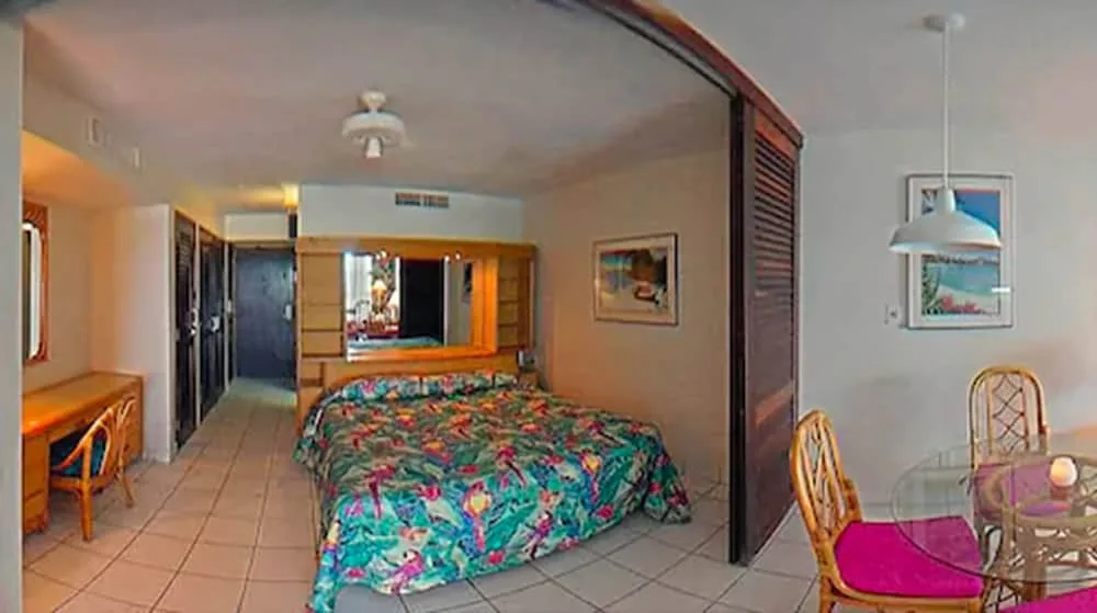 Guest room with colorful bedspread and dining area at Sapphire Beach Resort.