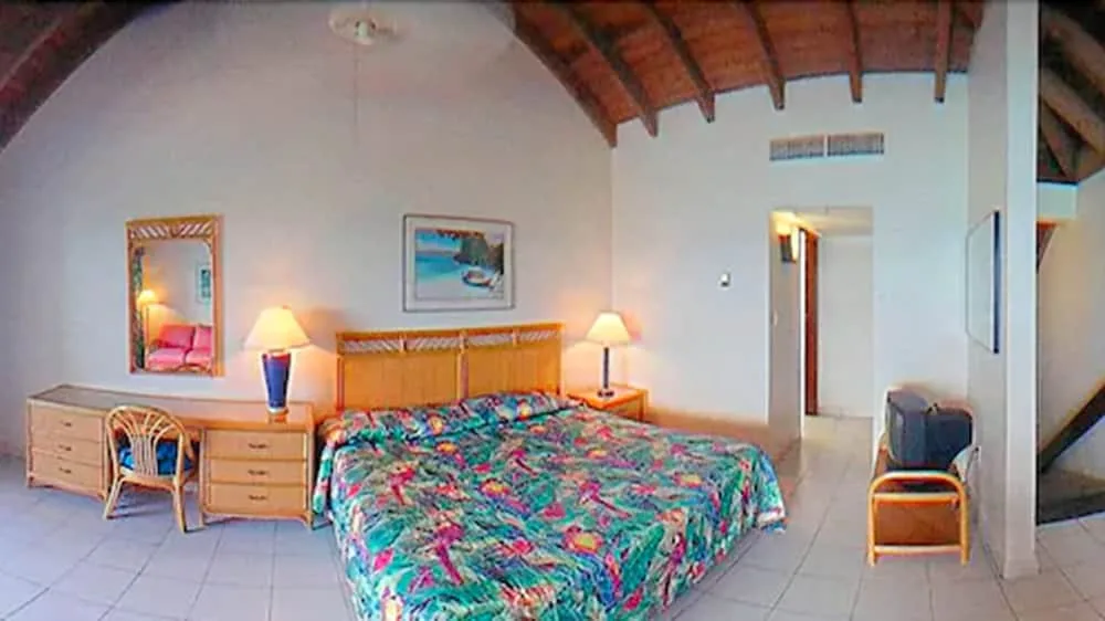 Guest room with king bed and tropical bedding at Sapphire Beach Resort.