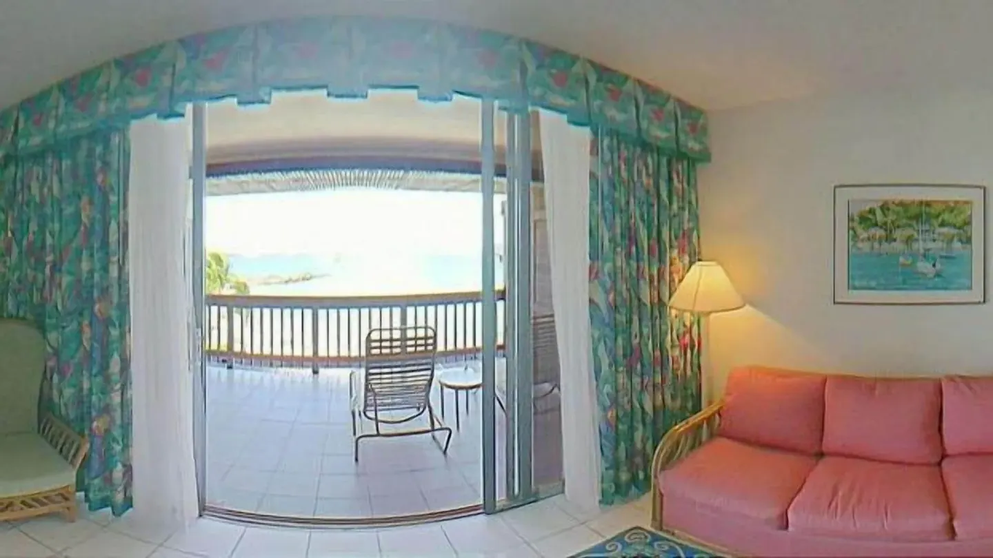 Living area with pink sofa and balcony view at Sapphire Beach Resort.