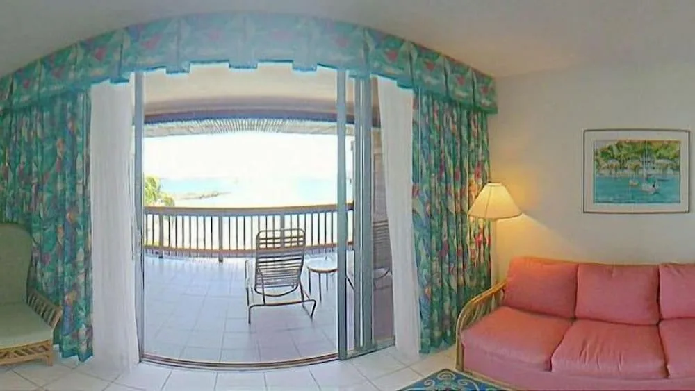 Living room with pink sofa and balcony doors at Sapphire Beach Resort.