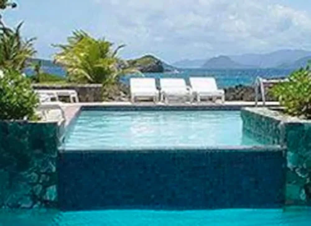 Pool edge with white loungers and ocean beyond at Sapphire Beach Resort.