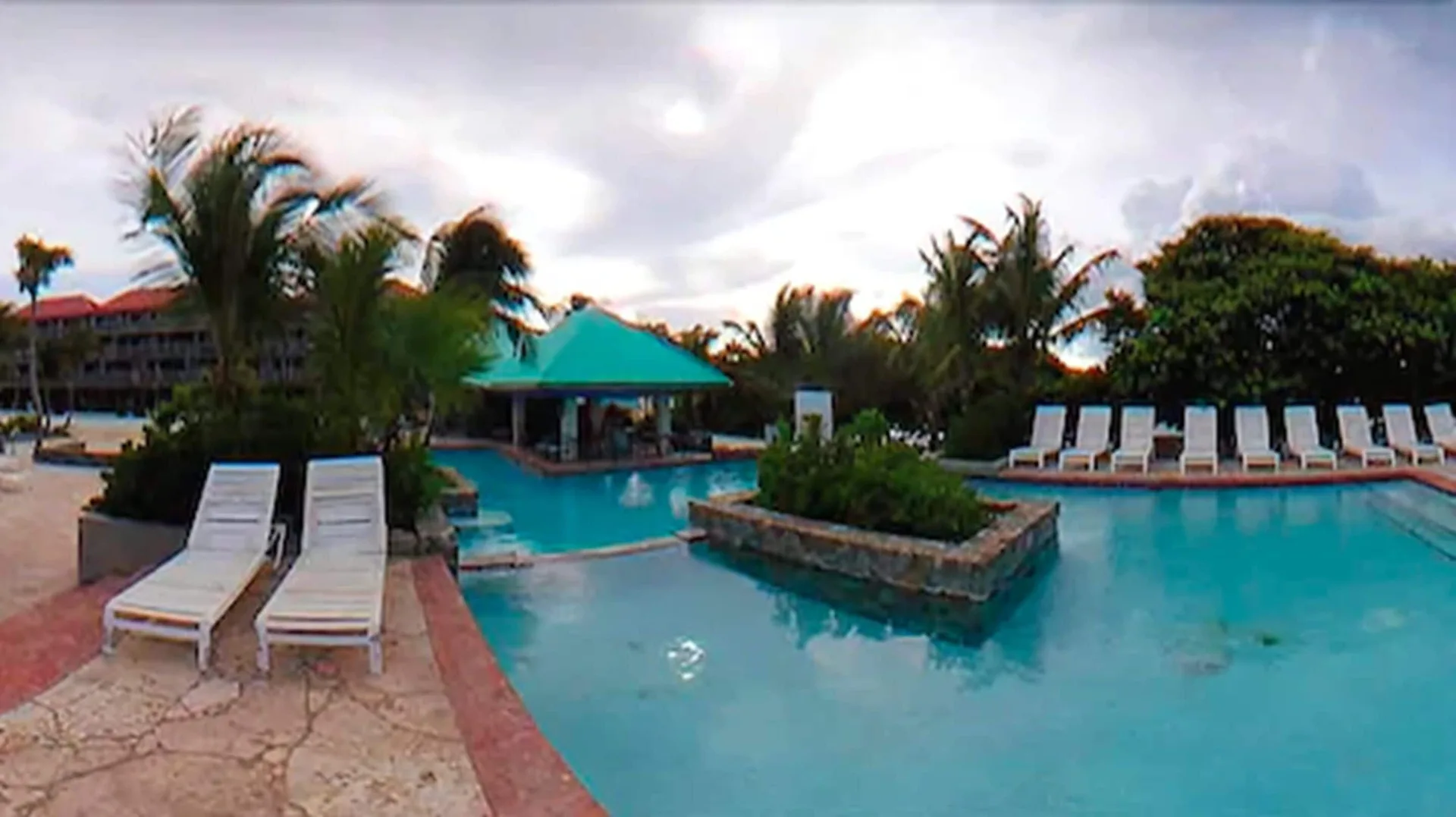 Resort pool with loungers, palms, and pavilion at Sapphire Beach Resort.