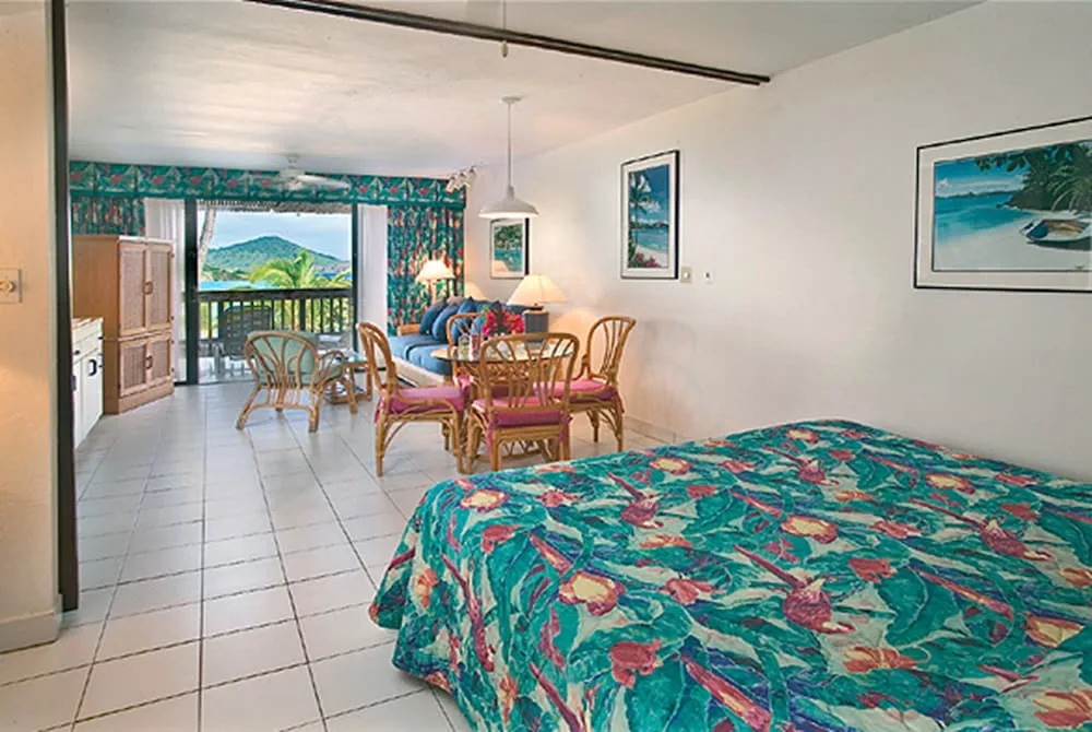 Studio guest room with bed, dining table, sofa, and balcony at Sapphire Beach Resort.