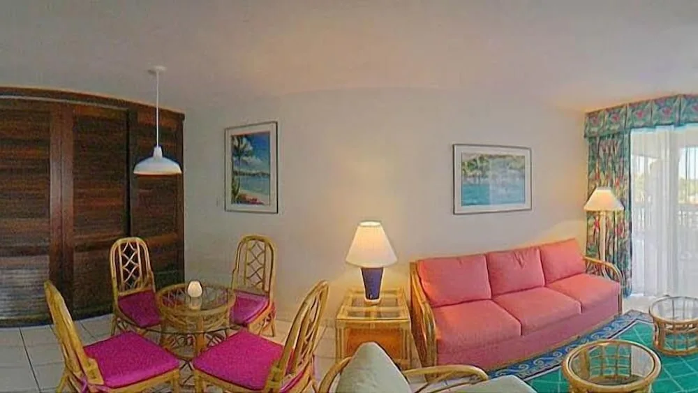 Living area with wicker dining set and pink sofa at Sapphire Beach Resort.