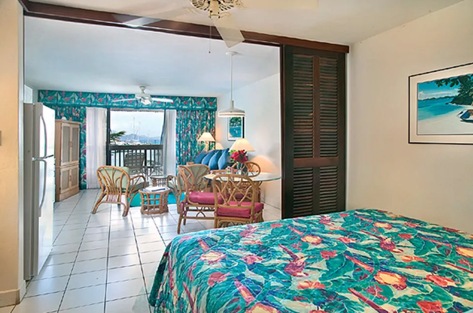 Standard studio suite bed and seating area with harbor balcony at Sapphire Beach Resort.