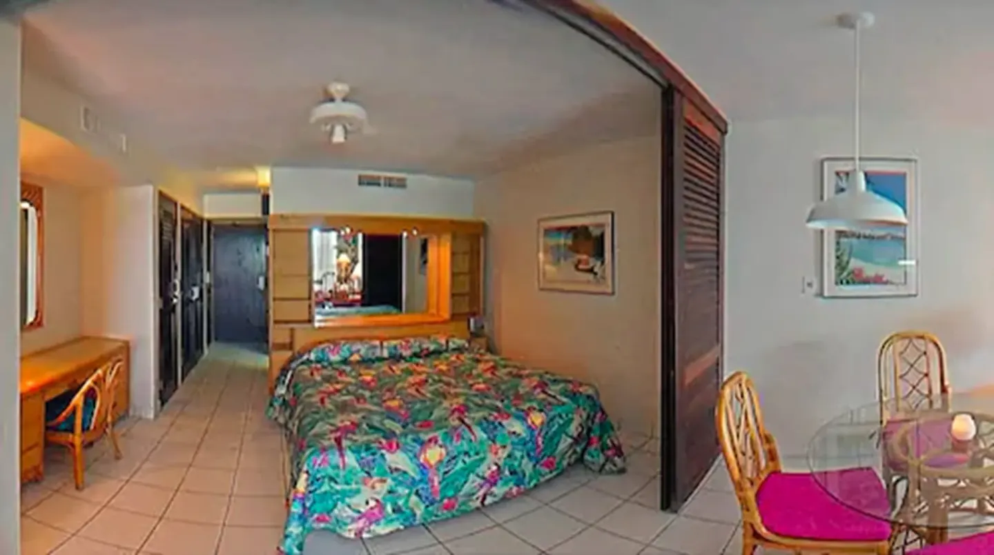 Standard studio suite bed, vanity, desk, and dining table at Sapphire Beach Resort.