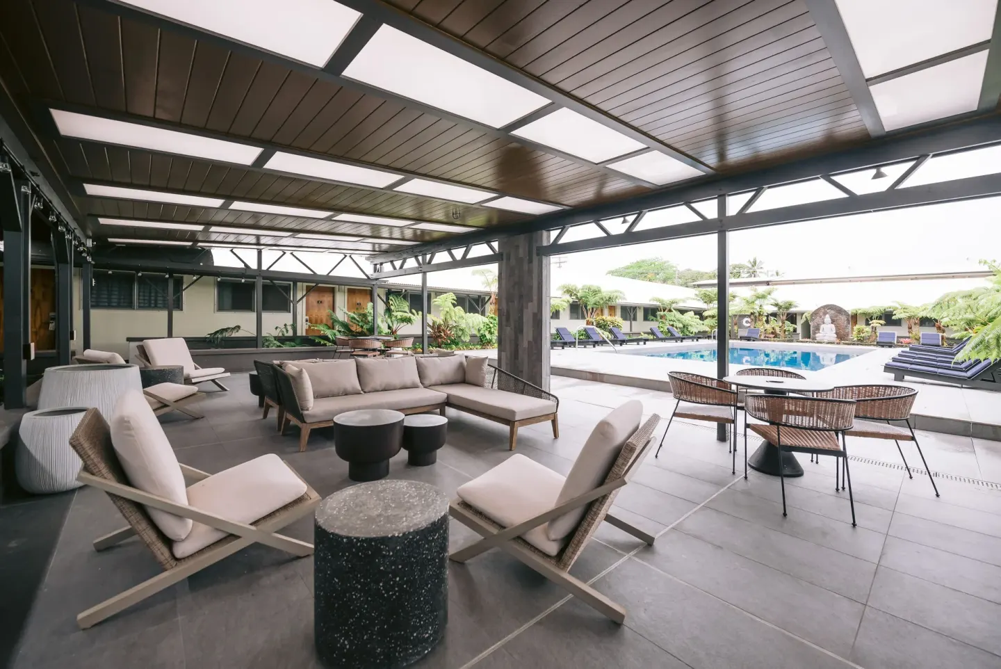Covered poolside lounge with sofas, chairs, and tables at SCP Hilo Hotel.