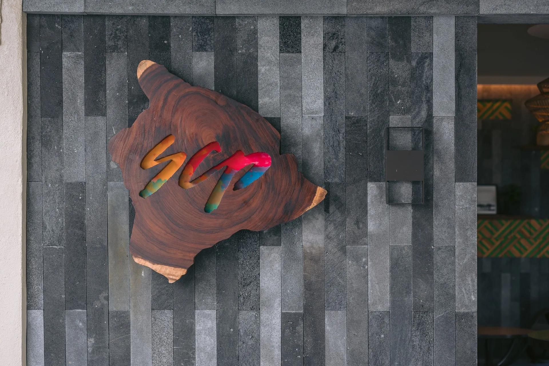 Wooden SCP wall sign on dark stone tile near the entrance at SCP Hilo Hotel.