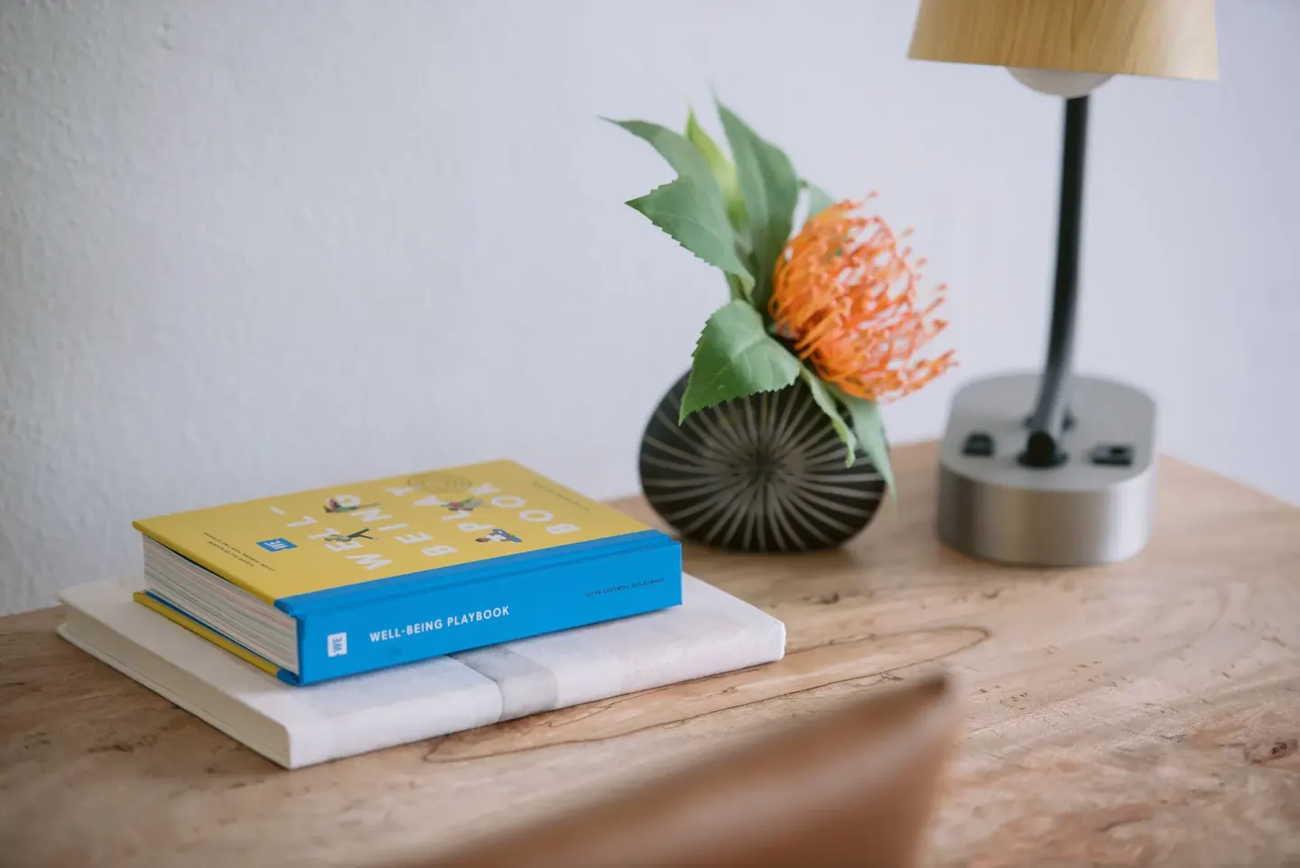 Desk vignette with books, lamp, and flower arrangement in a room at SCP Hilo Hotel.