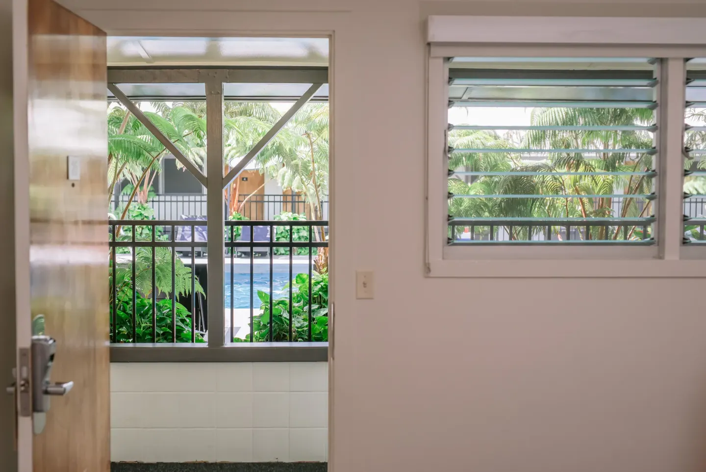 Guest room doorway and louvered window looking toward the pool at SCP Hilo Hotel.