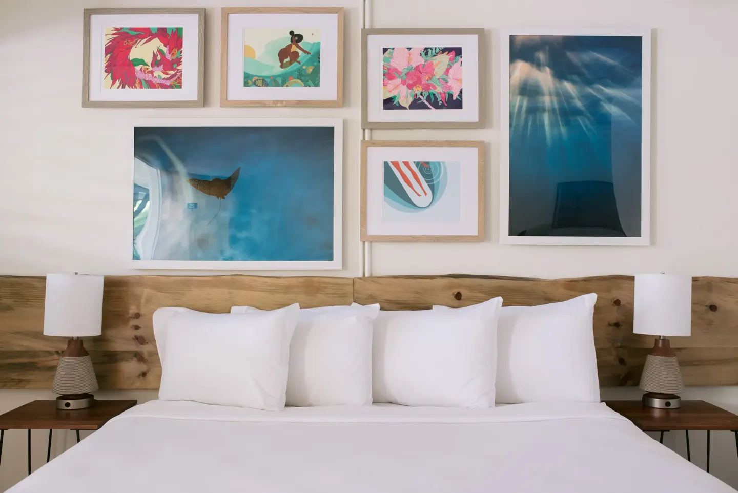 Close view of a king bed, wood headboard, lamps, and framed art at SCP Hilo Hotel.